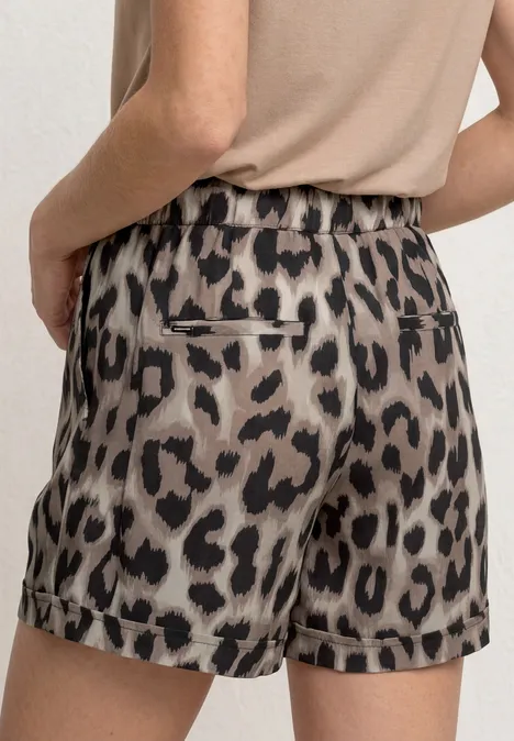 Close-up van een persoon van achteren in een beige-zwart luipaardprint short en beige top.