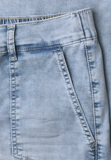 Nahaufnahme einer hellblauen Jeanshose mit sichtbarer Fronttasche und Nahtdetails.