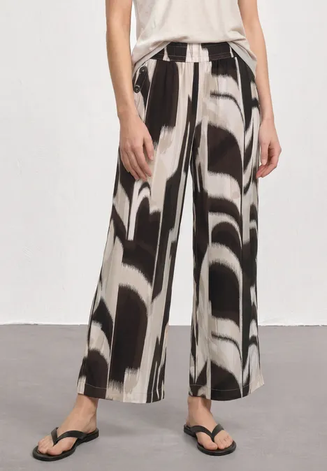High Waist Wide Leg Hose im Loose Fit espresso brown Weit geschnittene Hose mit abstraktem Schwarz-Weiß-Muster, kombiniert mit Flip-Flops.