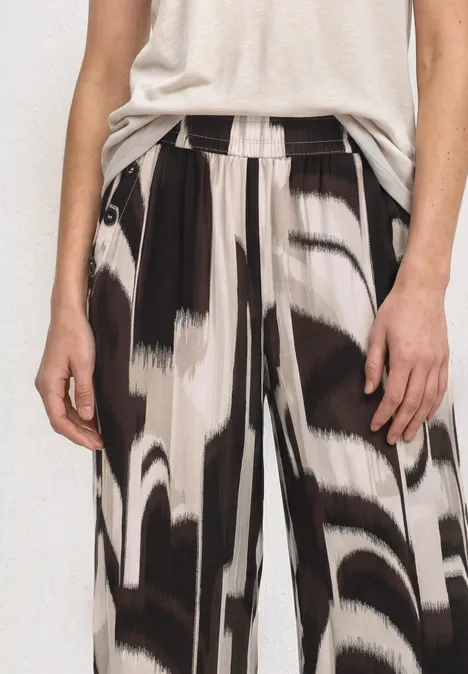 High Waist Wide Leg Hose im Loose Fit espresso brown Person trägt weite Hose mit abstraktem Schwarz-Weiß-Muster und helles Oberteil.