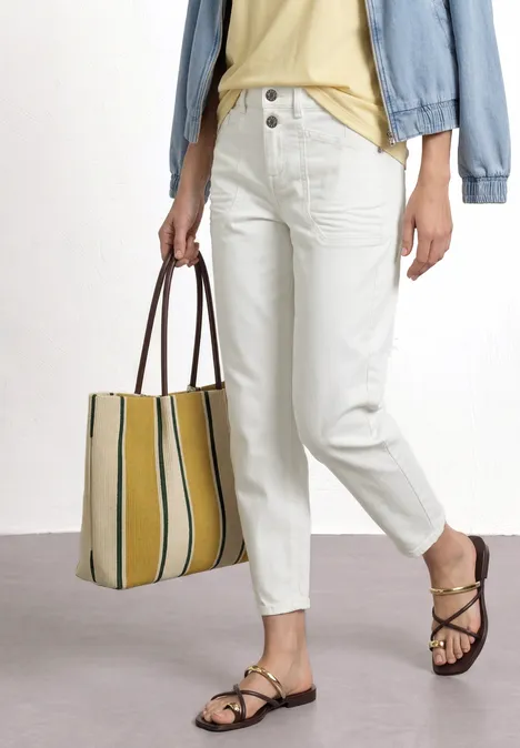 High Waist Barrel Leg Jeans im Loose Fit Off White washed Person in weißen High-Waist-Jeans, Jeansjacke, gelber Streifentasche und braunen Sandalen.
