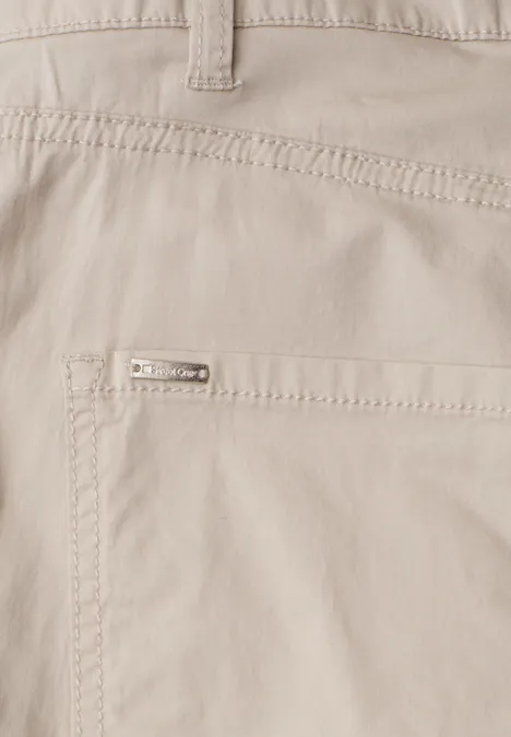 High Waist Barrel Leg Hose clay sand Close-up einer hellbeigen Hose mit aufgesetzter Tasche und kleinem Metalllogo.