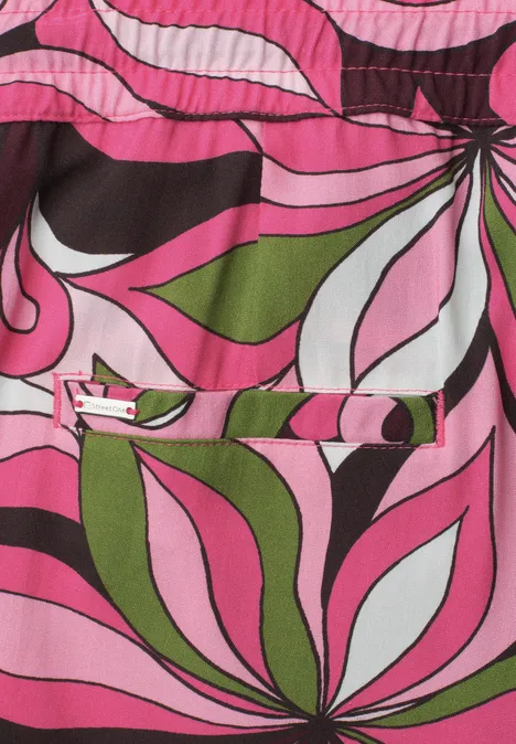 Felle psychedelische bloemenprint in roze, groen, wit en zwart op stof.