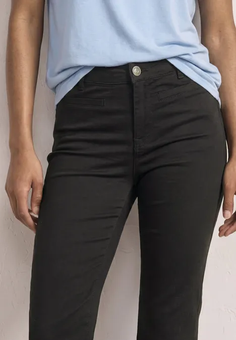 Nahaufnahme einer Person in schwarzer, hoch sitzender Jeans und hellblauem Shirt.