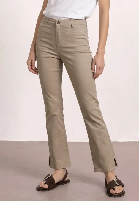 Beige High-Waist-Hose mit Schlitz am Saum, weißes T-Shirt und braune Sandalen.