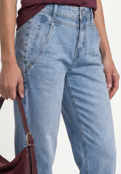 High Waist Barrel Leg Jeans im Loose Fit Light Blue Wash Eine Person trägt helle Jeans und hält eine braune Handtasche