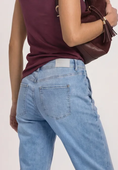 High Waist Barrel Leg Jeans im Loose Fit Light Blue Wash Rückansicht einer Person in hellblauen Jeans und burgunderrotem Top mit brauner Schultertasche.