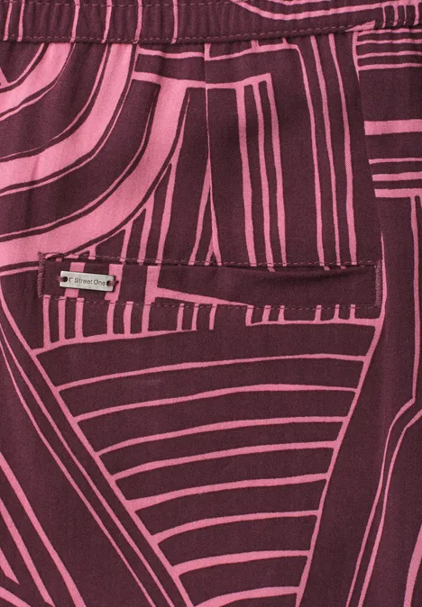 Motif abstrait sur tissu rose et bordeaux aux lignes géométriques.