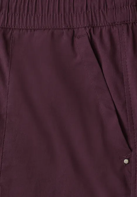 Broek met Straight Leg pijpen in casual pasvorm en omgeslagen boorden rustic rouge Close-up van bordeauxrode stoffen broek met elastische taille en zijzak