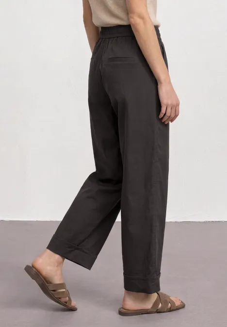 Straight Leg Hose im Casual Fit mit Turn-Up black coffee Rückenansicht einer Person in locker sitzender, dunkler Hose und braunen Sandalen.