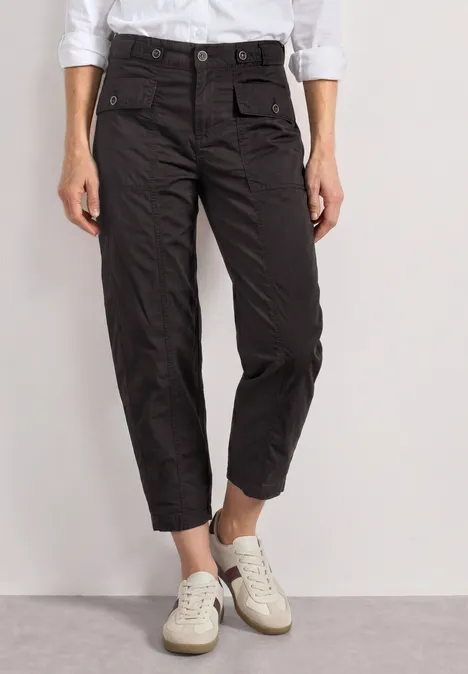 High Waist Barrel Leg Hose im Casual Fit black coffee Frau trägt schwarze, hochgeschnittene, knöchellange Cargo-Hosen mit großzügigen Taschen und weißen Sneakern.