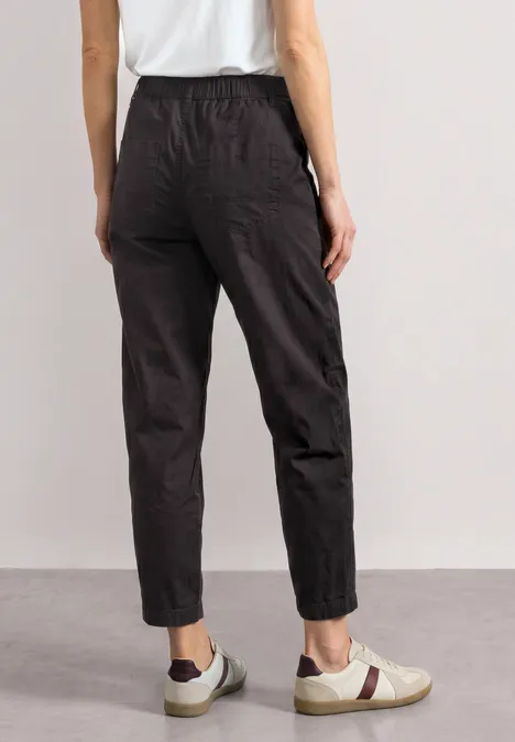 High Waist Barrel Leg Hose im Casual Fit black coffee Rückansicht einer in locker sitzenden schwarzen Hose und weißen Sneakern vor neutralem Hintergrund