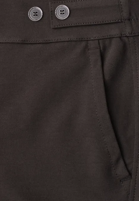 Close-up van een donkerbruine broek: zijzak en tailleband met twee knopen.