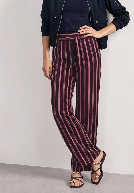 Mid Waist Wide Leg Hose mit Streifen dark clouded blush Frau trägt dunkelblaue Jacke, T-Shirt, locker geschnittene, rot-weiß gestreifte Hose und Sandalen.