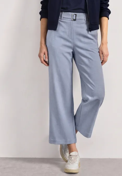 Lichtblauwe, hooggetailleerde culotte met riem, gecombineerd met witte sneakers.