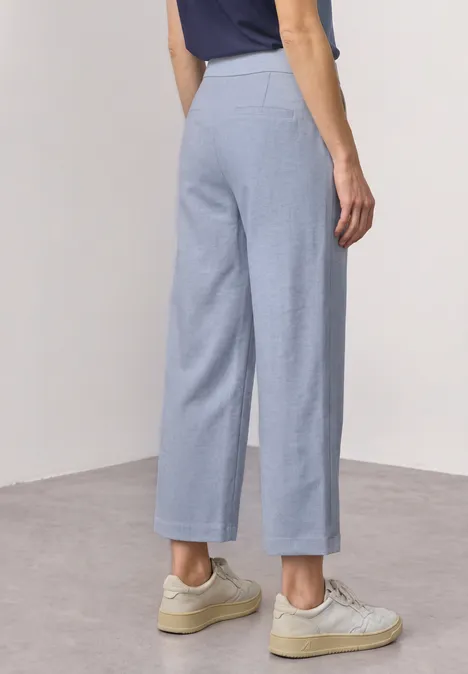 Lichtblauwe wijde broek van achteren gezien, gecombineerd met lichte sneakers.