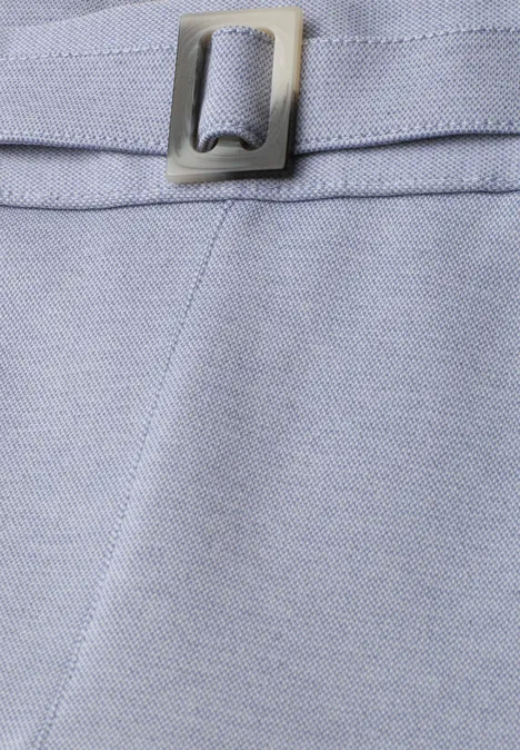 Close-up van lichtblauw stof met naad en zilverkleurige metalen gesp.