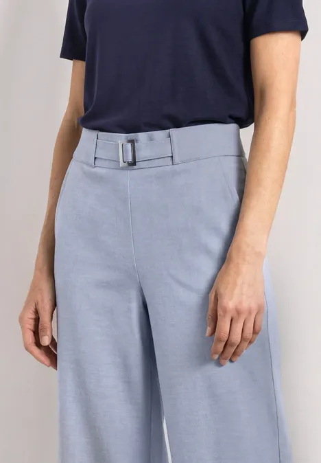 Marineblauw shirt en lichtblauwe, wijde pantalon met riem.