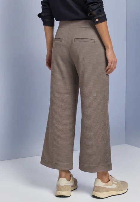 High Waist Culotte im Casual Fit black coffee Frau in weitem, knöchellangem beigen Stoffhose und hellen Sneakern, Rückansicht