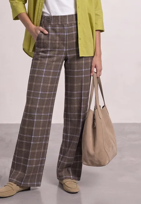 Weite braune Karohose im Karo-Look mit weißem T-Shirt, grünem Overshirt und beigem Shopper.