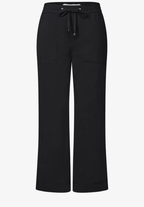 Zwarte, losvallende broek met trekkoord en wijde pijpen.