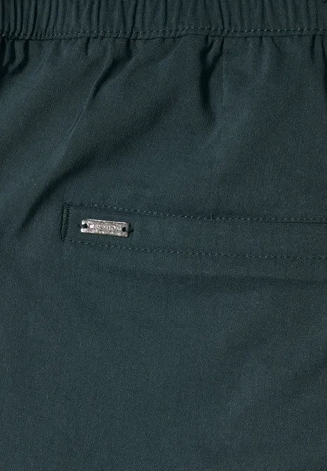 Nahaufnahme einer dunklen Hose mit Reißverschlusstasche und Metalllabel.