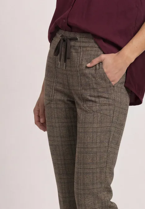 Mid Waist Slim Leg Hose im Loose Fit saddle brown Eine Person trägt karierte, hoch taillierte Stoffhose mit Kordelzug und Eingrifftaschen in Braun.