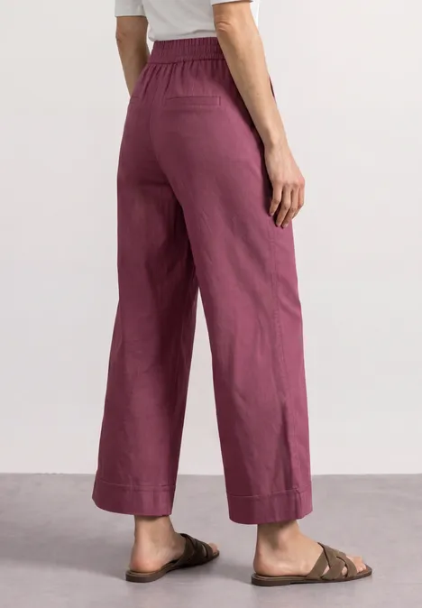 Straight Leg Hose im Casual Fit mit Turn-Up dark clouded blush Frau in lockeren, hochgeschnittenen violetten Leinenhosen und braunen Sandalen, seitlich von hinten fotografiert.