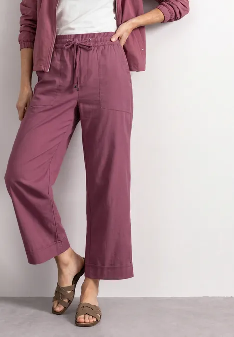 Straight Leg Hose im Casual Fit mit Turn-Up dark clouded blush Frau trägt weite, knöchellange Hose in Beerenton mit Tunnelzug, aufgesetzten Taschen und Sandalen.