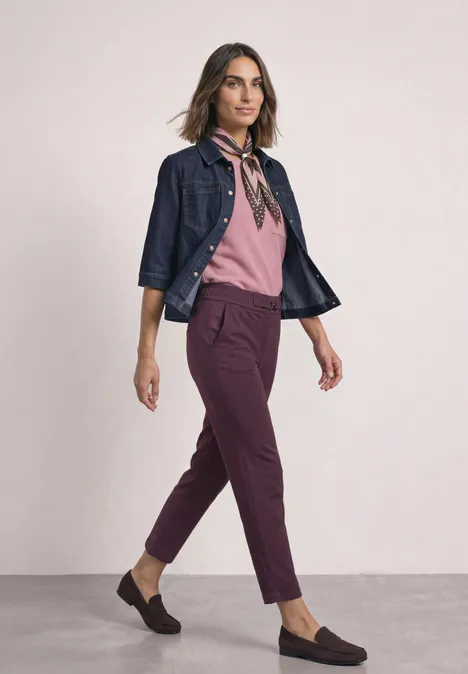 Slim Leg Hose mit Schnallendetail rustic rouge Frau im stylischen Outfit: rosa Bluse, dunkelrote Hose, Jeansjacke, Halstuch und schwarze Loafers.