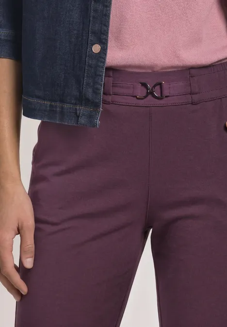 Slim Leg Hose mit Schnallendetail rustic rouge Unterkörper einer Person mit violetten Hosen, dekorativem Bundverschluss und Jeansjacke.