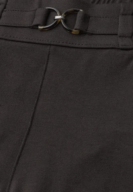Detail eines schwarzen Hosen- oder Rockbunds mit Gürtel und goldfarbenen Metallringen.