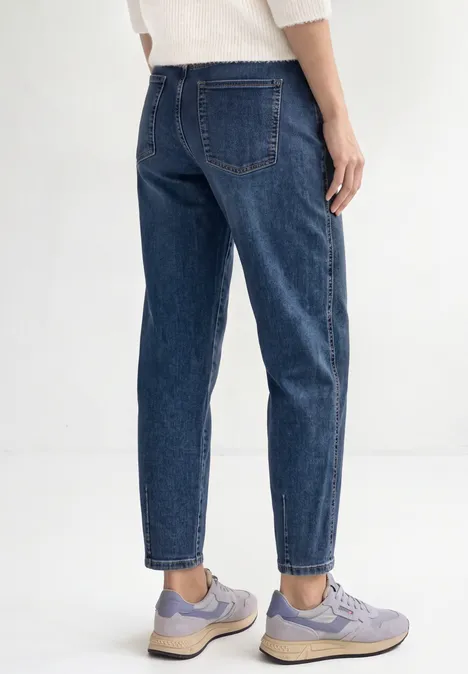 High Waist Barrel Leg Jeans im Loose Fit Mid Blue Random Washed Rückansicht einer Person in blauen Jeans und lila Sneakern