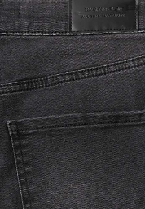 Close-up van een zwarte spijkerbroek met achterzak en zichtbaar label in de taille