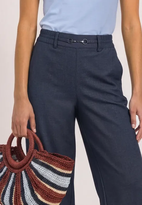 Straight Leg Hose mit Schnallendetail darkest blue Frau im hellblauen Top, dunkelblaue Hose und bunte Korbtasche
