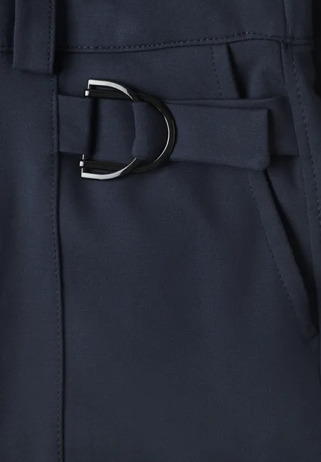 Dunkelblauer Stoff mit silbernem D-Ring an Gürtelband, Detailaufnahme neben einer Tasche.