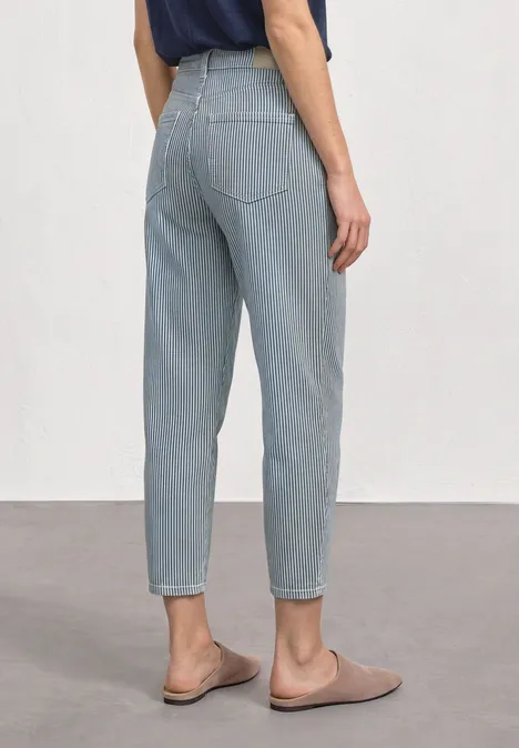 Vue arrière d'une personne en jean bleu clair taille haute et mocassins beiges.
