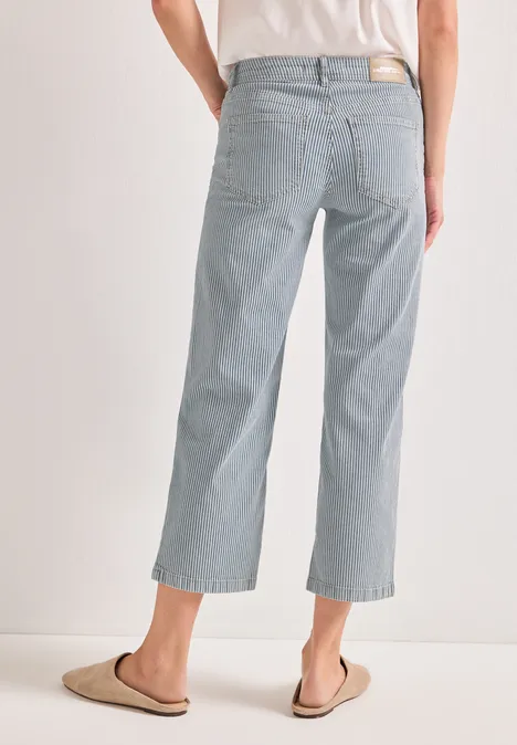 Vue arrière d'une personne en jean ample bleu clair, longueur cheville, et pantoufles.