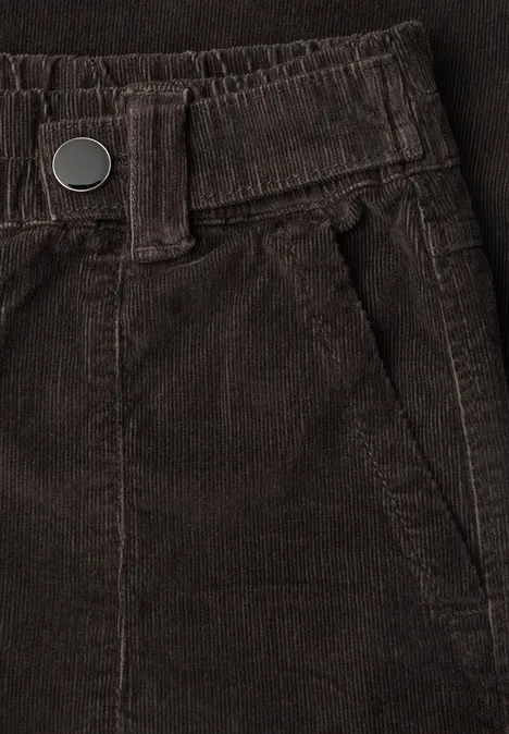Close-up van een bruine ribfluweelbroek met elastische taille, riemlussen en zijzak.