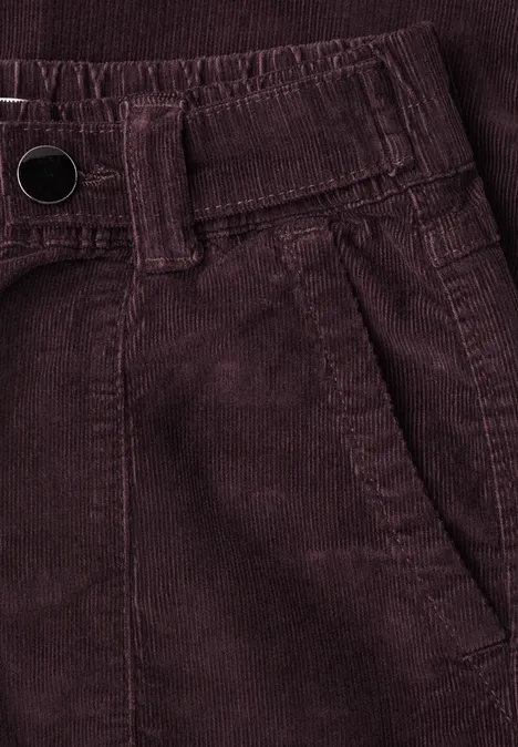 Nahaufnahme einer dunkelroten Cordhose mit Bund, Gürtelschlaufen und Seitentasche.