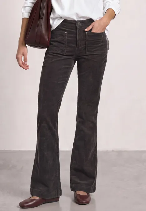 Schwarze Cordhose mit ausgestelltem Bein, hoher Taille, Taschen- und Nahtdetails, kombiniert mit braunen Loafers.