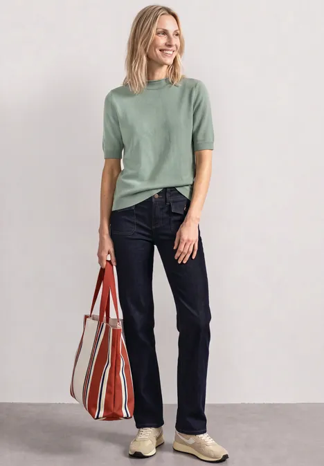 Mid Waist Straight Leg Jeans im Casual Fit Rinse Washed Frau mit grünem Shirt, Jeans und gestreifter Tasche