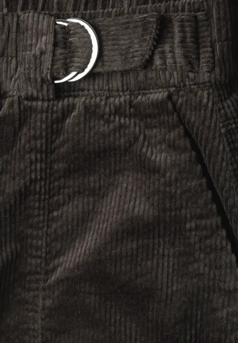 Close-up van een donkerbruine ribfluwelen broek met metalen D-ring in de taille en zijzak.