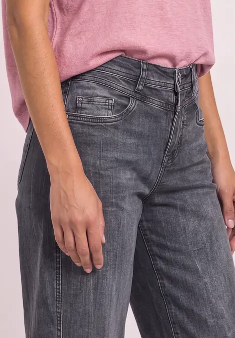 Person mit rosa T-Shirt und grauen Jeans, zu sehen von Taille bis Oberschenkel.