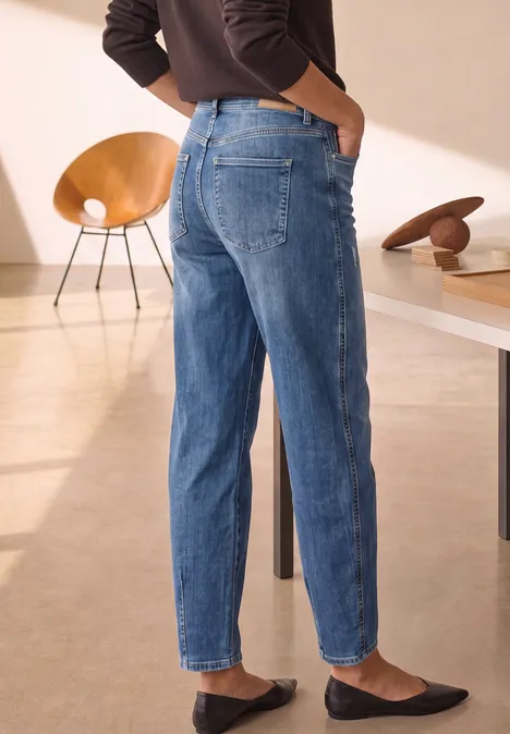 Relaxed Barrel Leg Jeans im Loose Fit Medium Blue Destory Washed Person in lockeren blauen Jeans und schwarzen Slippern steht in modernem Raum mit Möbeln.