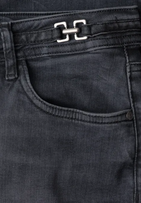 Nahaufnahme einer schwarzen Jeans mit Eingriffstasche und Metall-Logo am Bund.