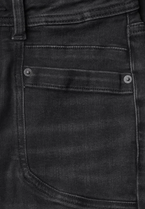 Nahaufnahme einer schwarzen Jeans-Tasche mit Ziernähten und Metallnieten