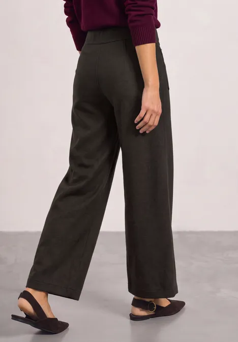Dunkelgraue, weite Hose mit Seitentaschen, schwarzer Sling-Ballerina und roter Pullover, seitliche Ansicht.