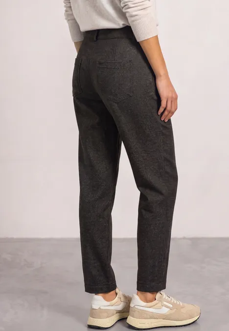 High Waist Tapered Leg Hose im Casual Fit black coffee Frau von hinten in dunkelgrauen Stoffhosen und beigen Sneakern vor neutralem Hintergrund.