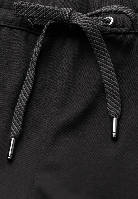 Schwarzer Textilstoff mit mittig geknotetem Kordelzug und silberfarbenen Metallenden.